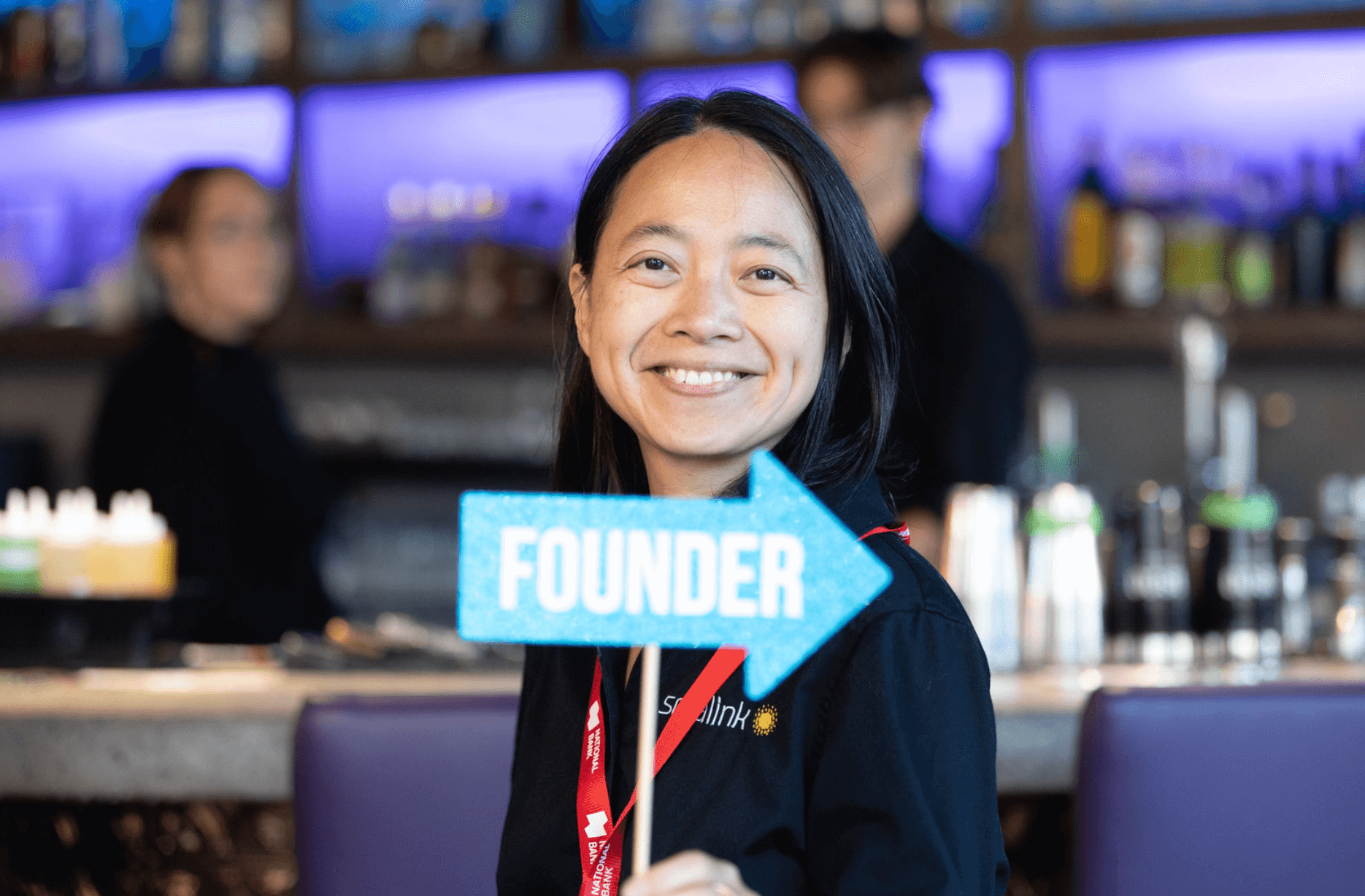 Yun Yao at L-SPARKS's 10th cohort celebration, smiling and holding up a sign that says "FOUNDER", made by Amber at Propmaster.
