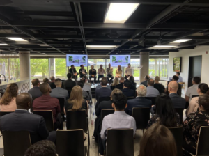A view of ULI Ottawa's event from behind the crowd, showing the busy room and the panelists on stage. 