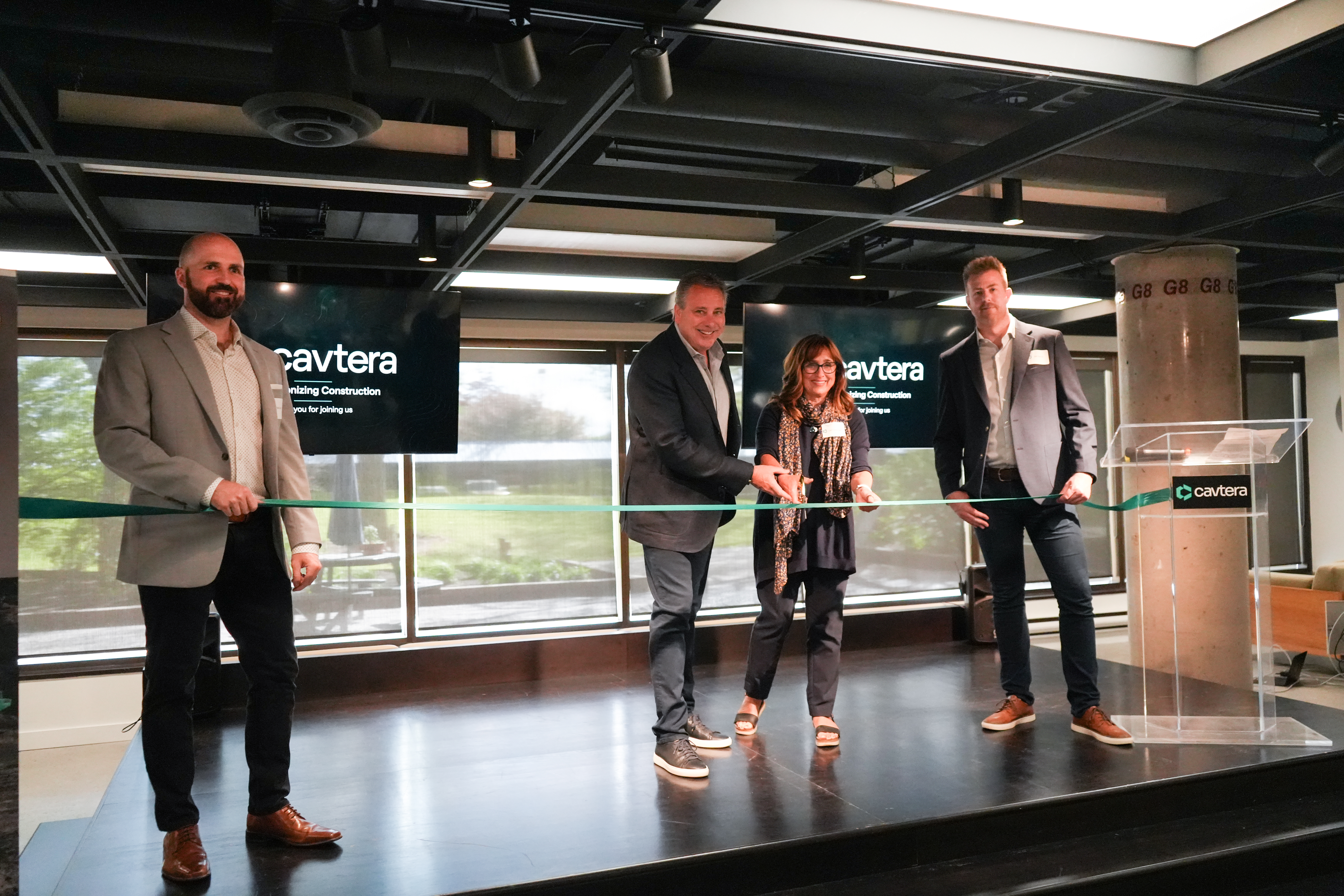 Cavtera ribbon-cutting at Hub350 in Kanata North. Leaders on stage smile as they cut the ribbon.